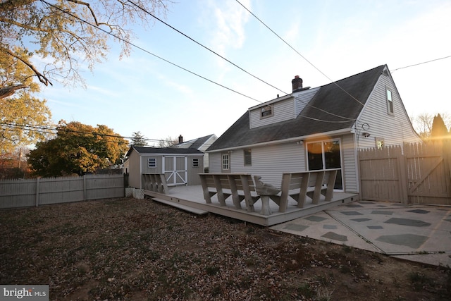 rear view of property with a storage unit and a wooden deck