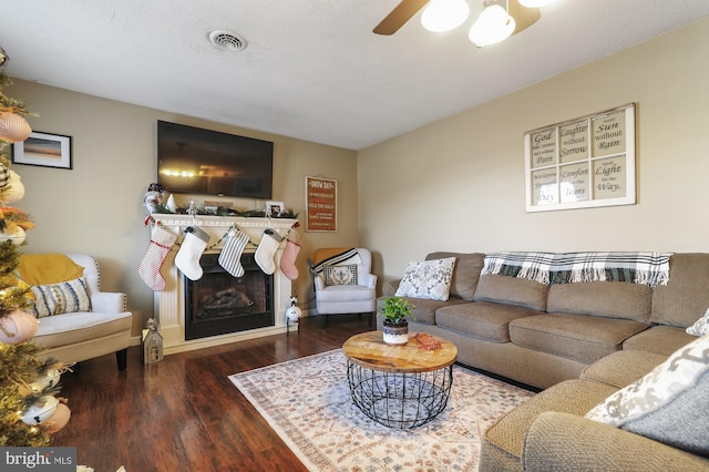 living room featuring ceiling fan, dark wood-type flooring, and a textured ceiling