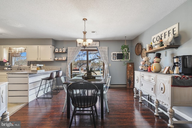 dining room featuring a textured ceiling, dark hardwood / wood-style flooring, a baseboard heating unit, and a notable chandelier