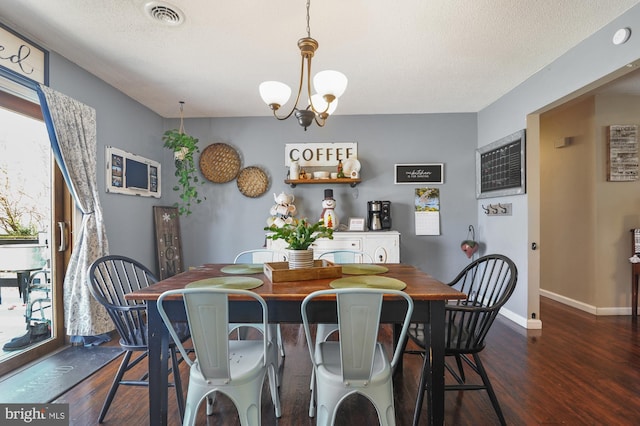 dining room featuring dark hardwood / wood-style flooring, a textured ceiling, and a chandelier