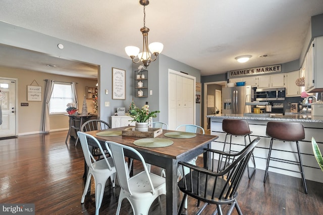 dining space featuring dark hardwood / wood-style flooring, a textured ceiling, and a notable chandelier