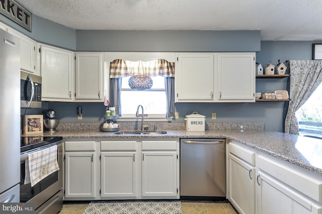 kitchen featuring appliances with stainless steel finishes, white cabinetry, a healthy amount of sunlight, and sink