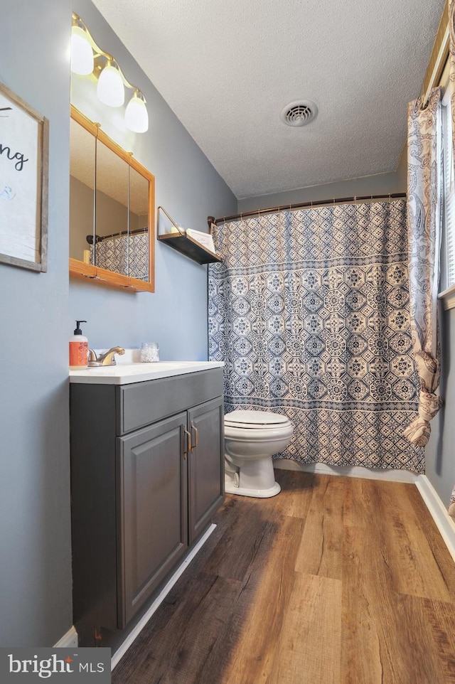 bathroom with a textured ceiling, vanity, hardwood / wood-style flooring, and toilet