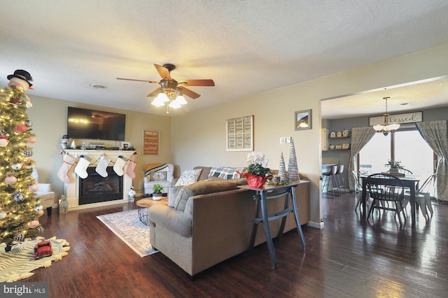 living room with dark hardwood / wood-style floors, ceiling fan, and a textured ceiling