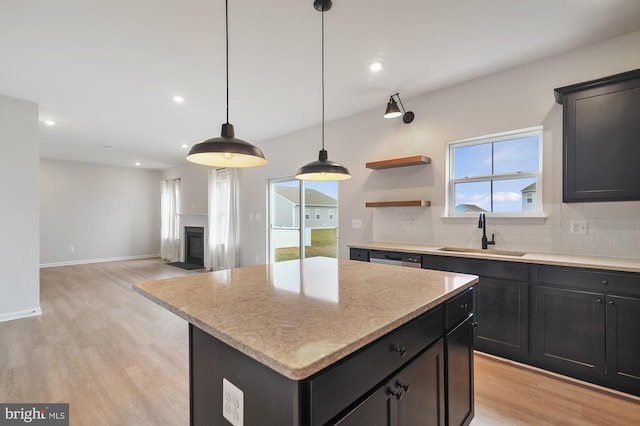 kitchen featuring sink, light hardwood / wood-style flooring, pendant lighting, decorative backsplash, and a kitchen island