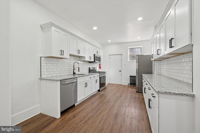 kitchen with light stone countertops, white cabinetry, stainless steel appliances, and dark wood-type flooring