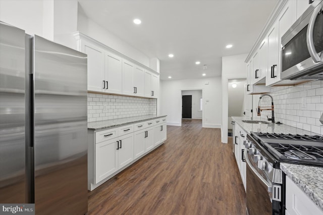 kitchen with sink, dark wood-type flooring, stainless steel appliances, tasteful backsplash, and white cabinets