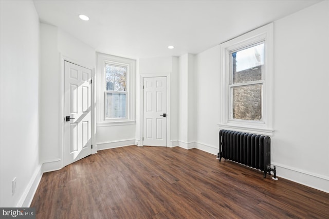 empty room with dark hardwood / wood-style floors and radiator heating unit