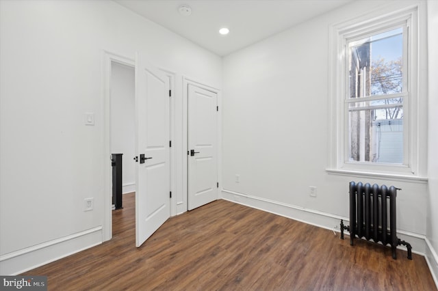 unfurnished room with radiator heating unit and dark wood-type flooring