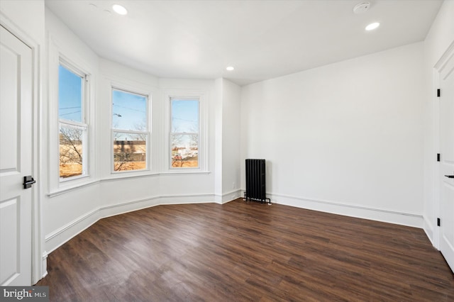 empty room featuring dark hardwood / wood-style flooring and radiator heating unit