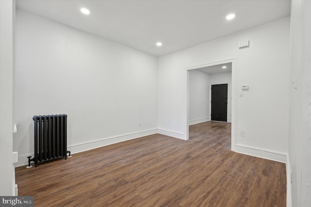 unfurnished room with radiator heating unit and dark hardwood / wood-style flooring