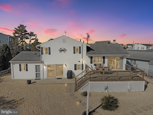 back house at dusk with a wooden deck