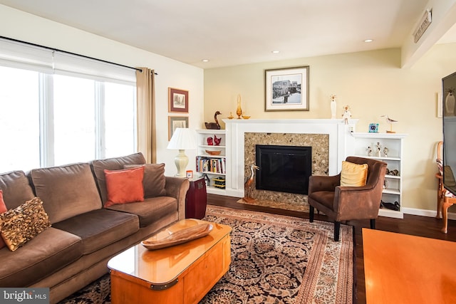 living room featuring a high end fireplace and dark wood-type flooring