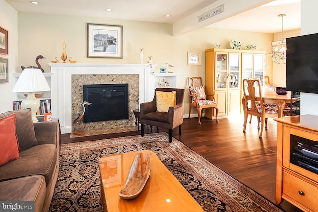 living room featuring a notable chandelier, dark hardwood / wood-style floors, and a fireplace