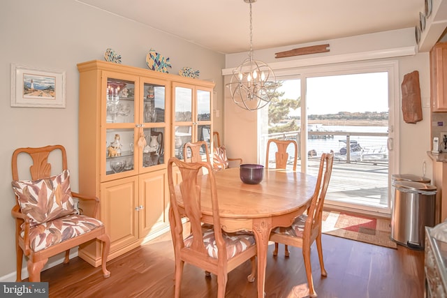 dining room with a water view, wood-type flooring, and an inviting chandelier