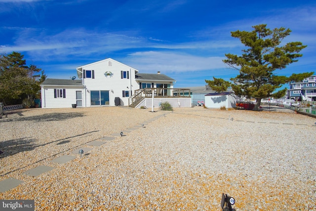 rear view of property featuring a storage shed and a wooden deck