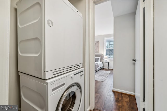 laundry area featuring stacked washing maching and dryer and dark wood-type flooring