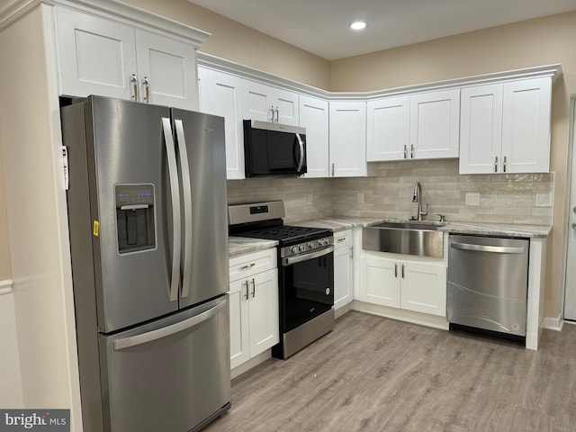 kitchen featuring sink, stainless steel appliances, light hardwood / wood-style floors, light stone countertops, and white cabinets