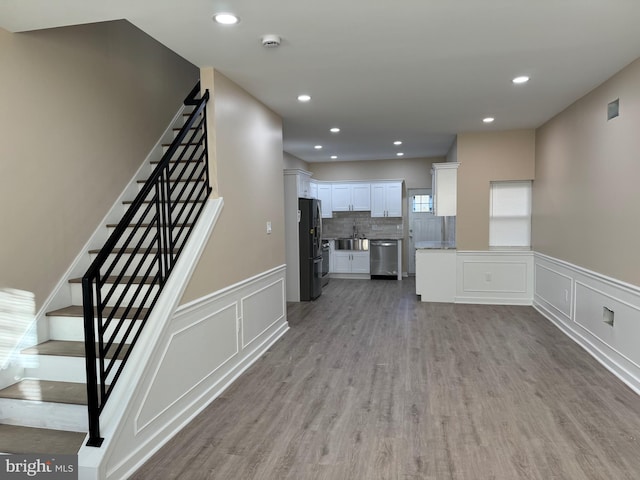 unfurnished living room featuring sink and light hardwood / wood-style floors