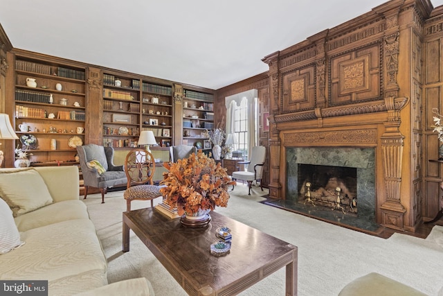 carpeted living room featuring a fireplace, built in features, and wooden walls