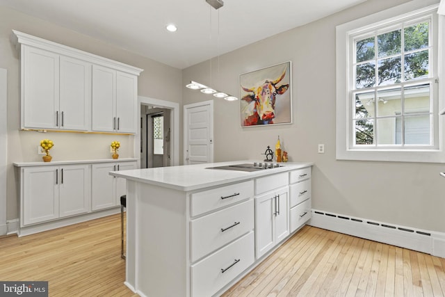 kitchen featuring white cabinets, pendant lighting, light hardwood / wood-style floors, and black electric cooktop