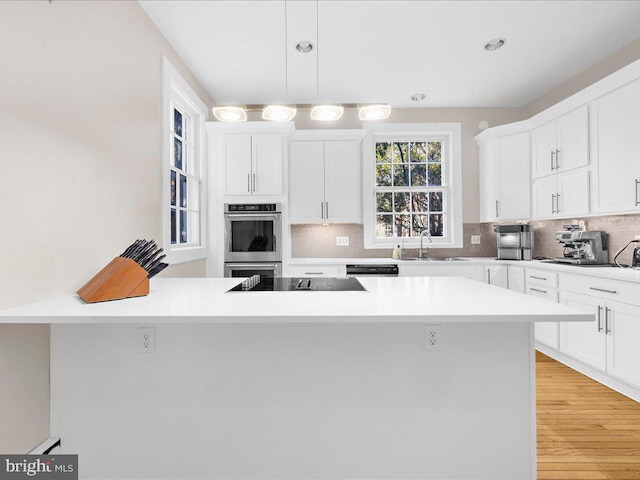 kitchen featuring black appliances, decorative backsplash, sink, and light hardwood / wood-style flooring