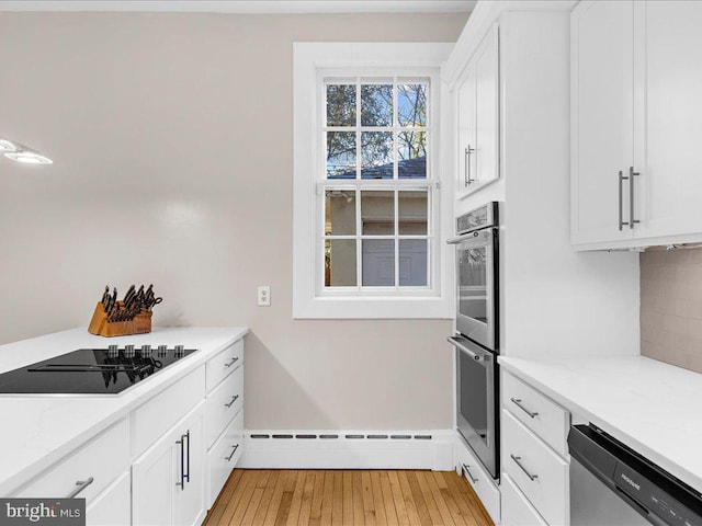 kitchen featuring stainless steel appliances, tasteful backsplash, a baseboard heating unit, white cabinets, and light wood-type flooring