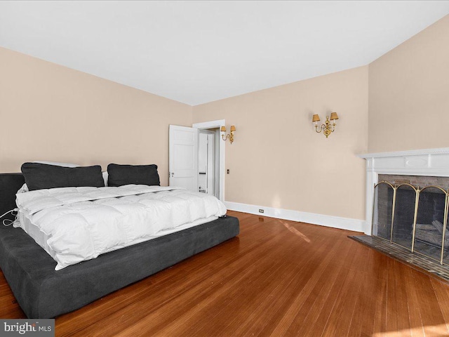 bedroom featuring wood-type flooring and a brick fireplace