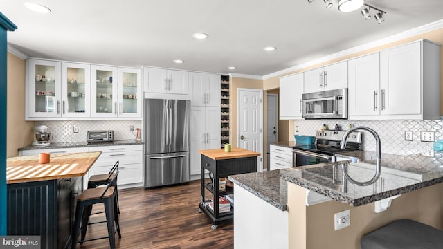 kitchen with a breakfast bar, white cabinetry, dark wood-type flooring, and stainless steel appliances