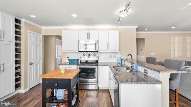 kitchen featuring stainless steel appliances, sink, white cabinets, dark hardwood / wood-style floors, and a breakfast bar area