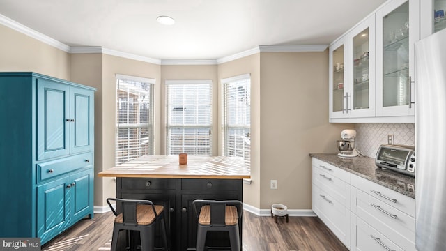 kitchen with a healthy amount of sunlight, light stone counters, white cabinetry, and dark wood-type flooring