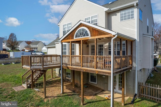 rear view of property featuring french doors, a deck, and a lawn