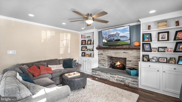 living room featuring dark hardwood / wood-style flooring, built in shelves, ceiling fan, crown molding, and a fireplace