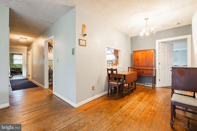 dining room with a notable chandelier, wood-type flooring, and a textured ceiling