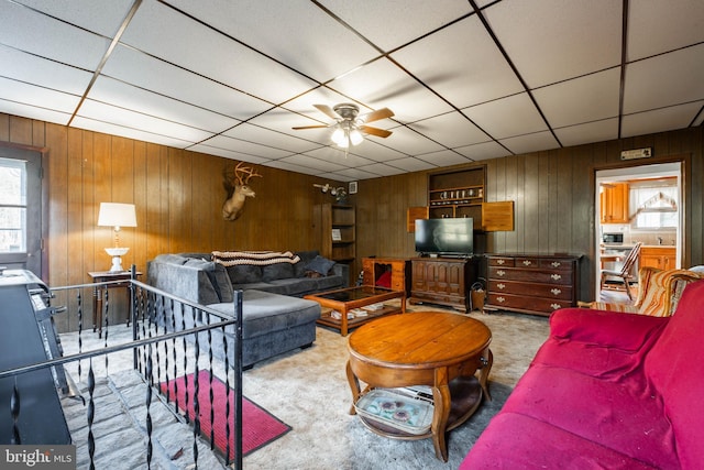 living room with wood walls, plenty of natural light, and ceiling fan