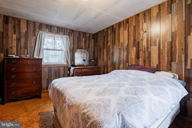 bedroom featuring dark colored carpet and wood walls