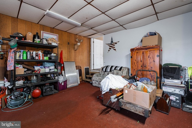 interior space featuring carpet, a drop ceiling, and wood walls