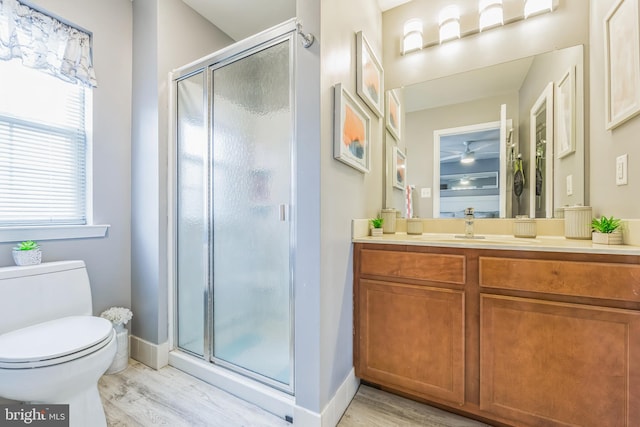 bathroom with hardwood / wood-style floors, vanity, a shower with door, and toilet