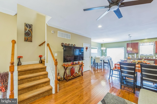 interior space with ceiling fan with notable chandelier, ornamental molding, sink, and light hardwood / wood-style flooring