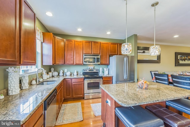 kitchen with sink, hanging light fixtures, light hardwood / wood-style floors, a breakfast bar, and appliances with stainless steel finishes