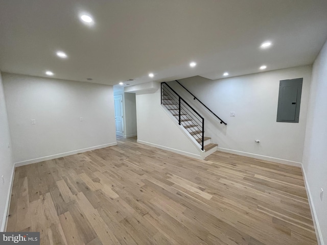 basement featuring electric panel and light hardwood / wood-style floors