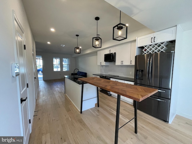 kitchen with backsplash, stainless steel appliances, pendant lighting, light hardwood / wood-style flooring, and white cabinetry