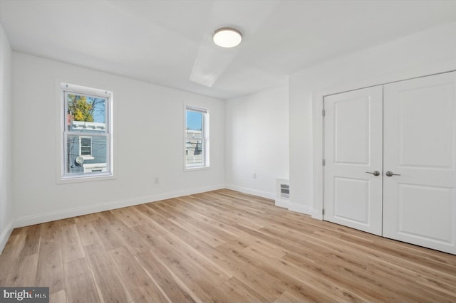 unfurnished bedroom with a closet and light wood-type flooring