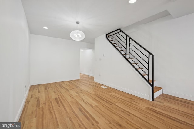 unfurnished living room with light hardwood / wood-style flooring and a notable chandelier