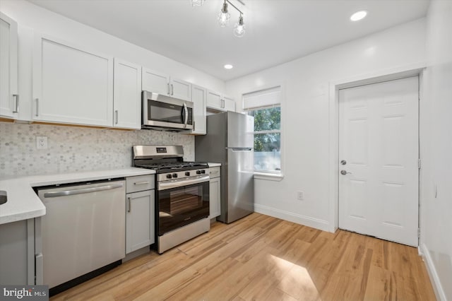 kitchen featuring light hardwood / wood-style floors, white cabinetry, appliances with stainless steel finishes, and tasteful backsplash