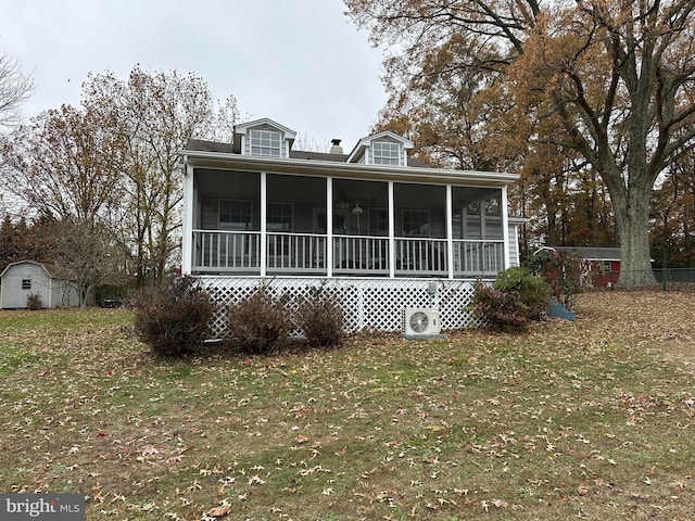 view of front of property featuring a sunroom, a storage unit, and a front yard