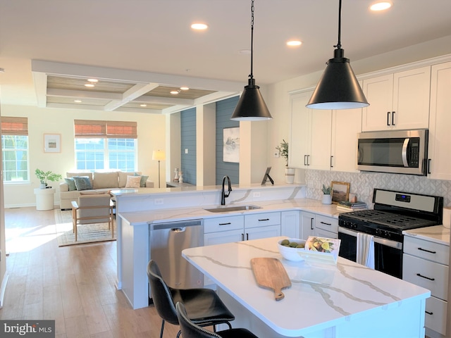 kitchen with a center island, white cabinets, sink, light hardwood / wood-style floors, and stainless steel appliances