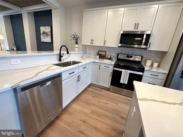 kitchen with white cabinets, appliances with stainless steel finishes, tasteful backsplash, and sink