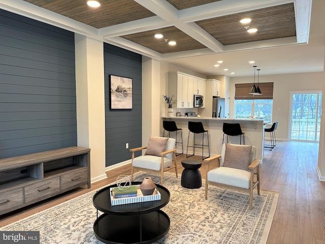 living room featuring beamed ceiling, wood walls, light wood-type flooring, and coffered ceiling