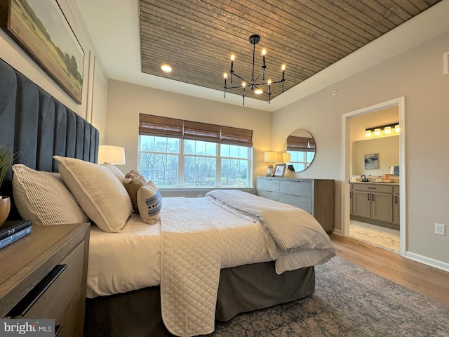 bedroom with ensuite bath, wood ceiling, a chandelier, and light hardwood / wood-style flooring